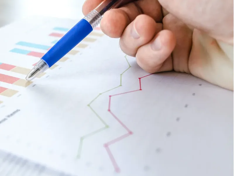 Une main trace une courbe ascendante au stylo sur un graphique
