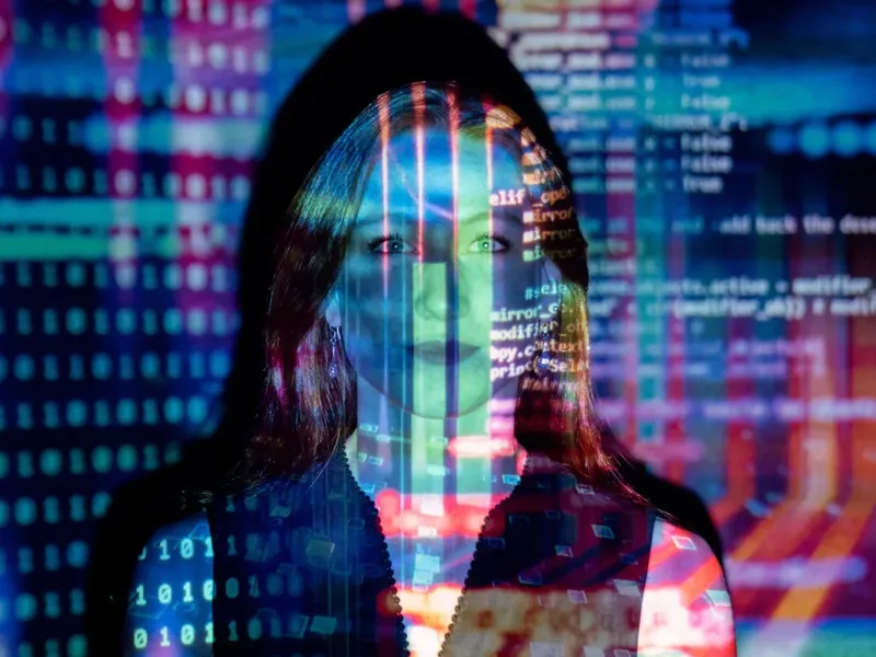 Une silhouette encapuchonnée devant un mur de code bleu