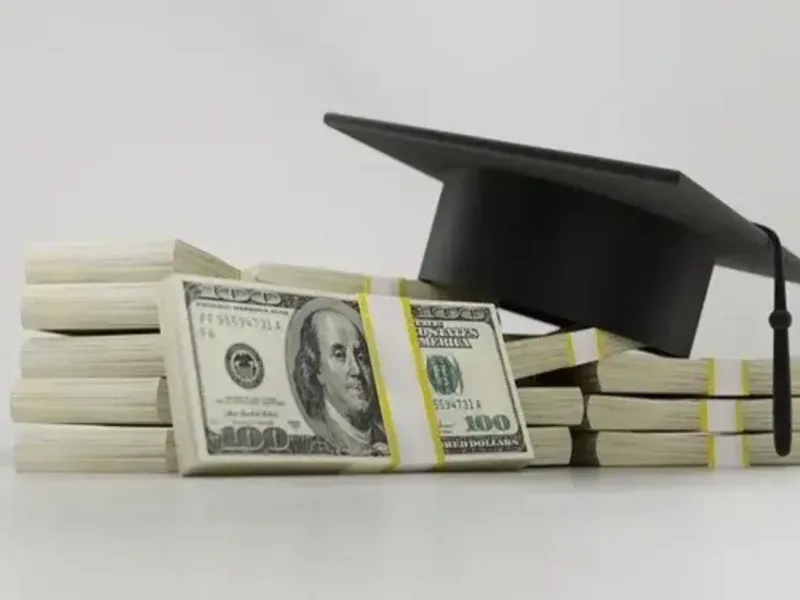 Une toque de diplômé posée sur des liasses de billets