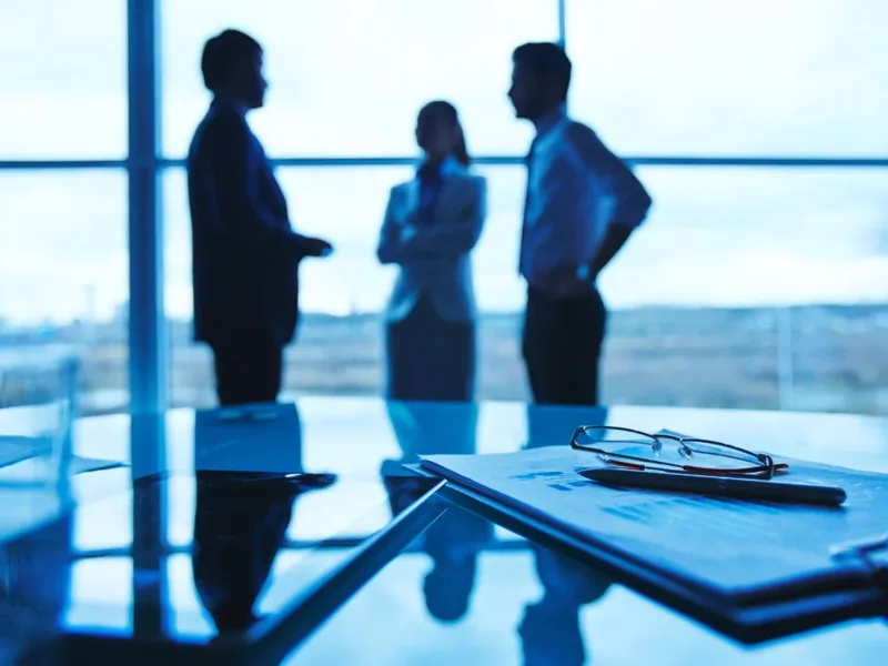 Silhouettes de collègues en discussion, à contre-jour dans un bureau