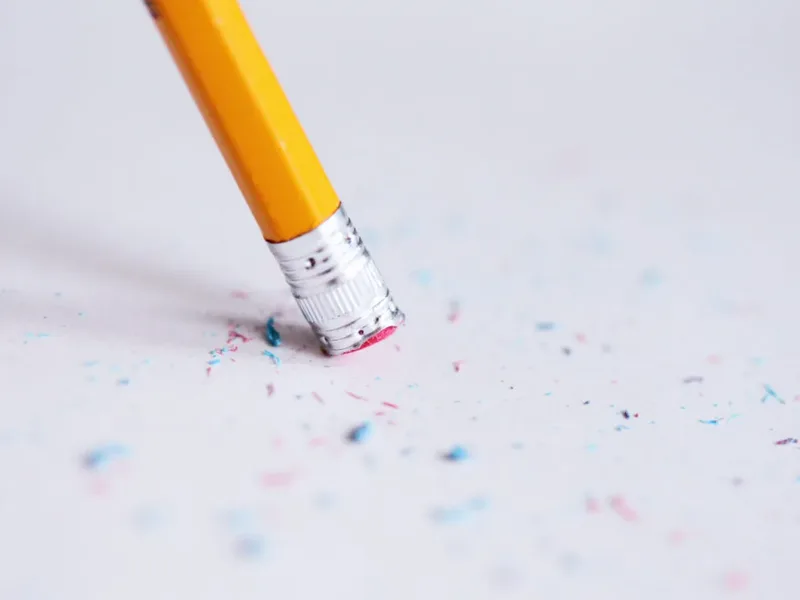Une gomme de crayon efface une trace sur une feuille blanche